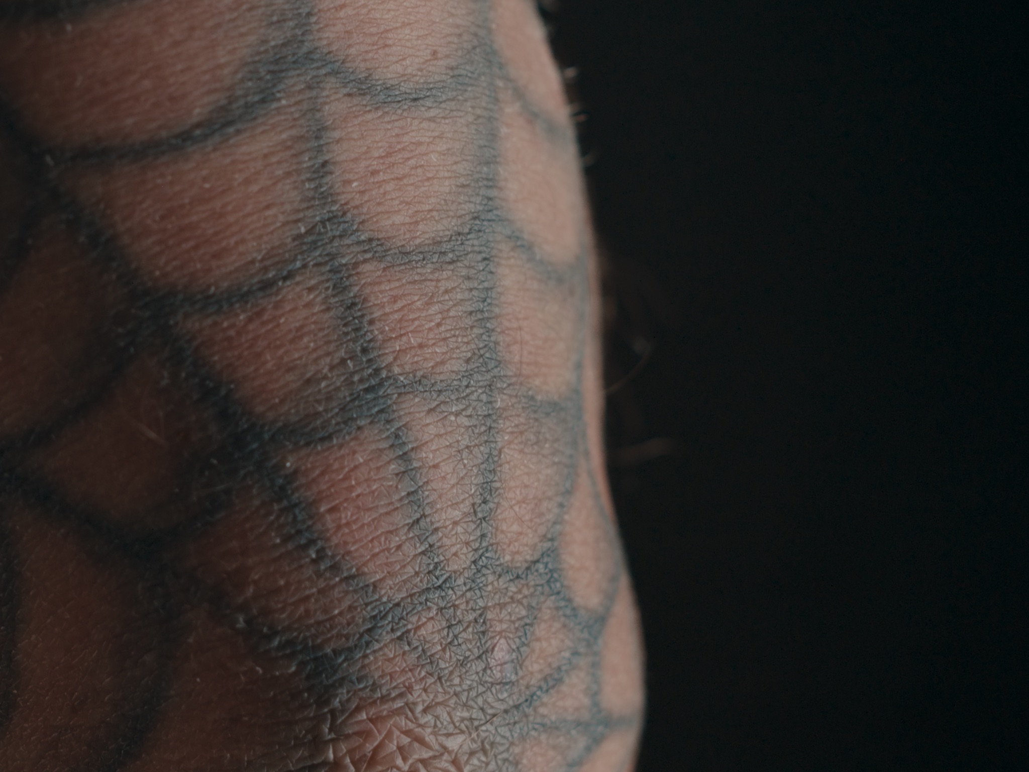 Close-up of a spiderweb tattoo on an elbow.