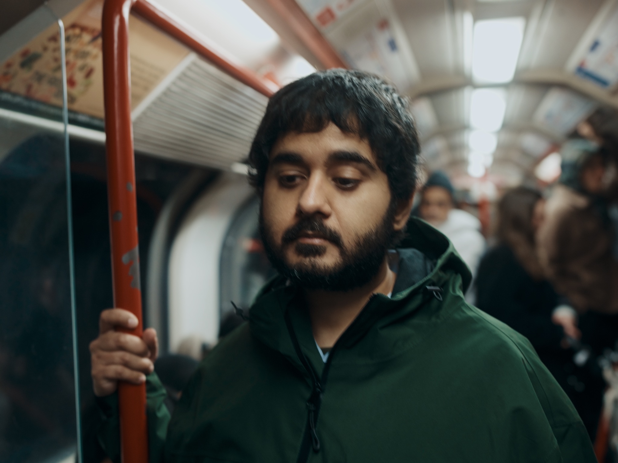 Sohail riding the London Underground, holding a rail.