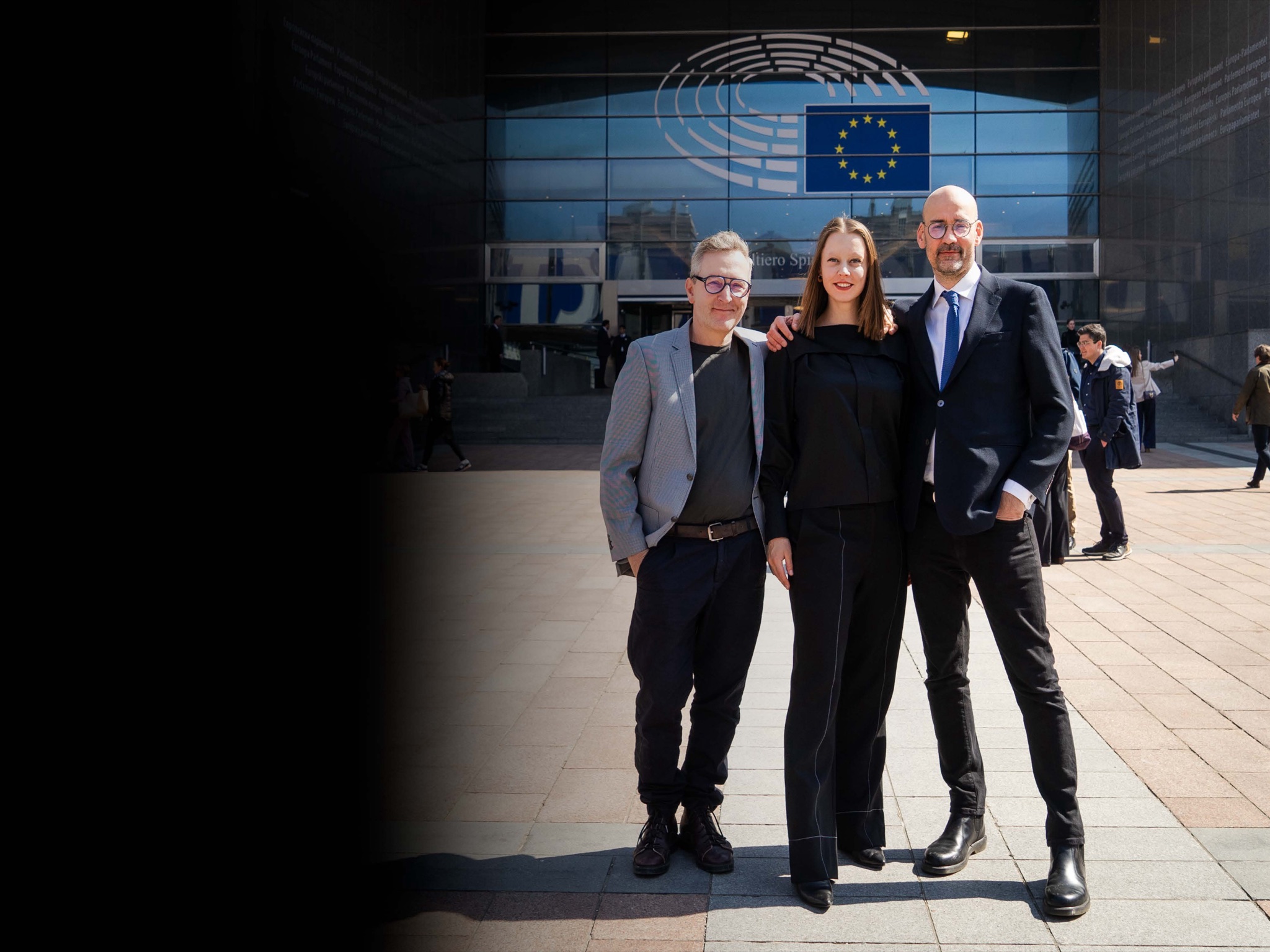 Anna Jochymek, Michał P. Garapich and Rafał Soborski standing in front of the European Parliament.