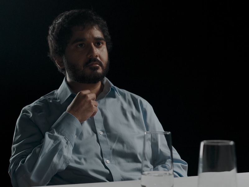 Sohail at the table, a glass of water in the foreground.